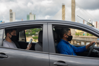 Motorista de aplicativo conduz veículo enquanto passageiro utiliza celular durante deslocamento urbano em Rondônia