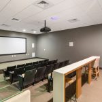 Sala de cinema moderna e vazia, com fileiras de poltronas voltadas para a tela.