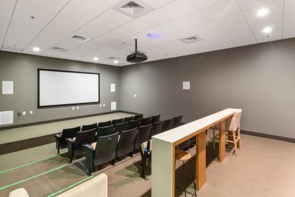 Sala de cinema moderna e vazia, com fileiras de poltronas voltadas para a tela.