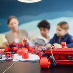 Grupo de crianças trabalha em um projeto de robótica em ambiente de educação tecnológica.